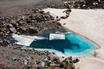 A beautiful turquoise lake on one of the slopes of Elbrus mount. The lake is formed from a nearby melting glacier. The altitude is 3500 meters.