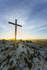Christian symbol, Wooden cross on the top of a hill at sunrise. 