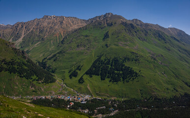 Elbrus region. The village of Terskol Below in the valley of the Baksan River from the slope of Mount Cheget. July 2020. Landscape view in the east of mount from Cheget mount. Kabardino-Balkaria
