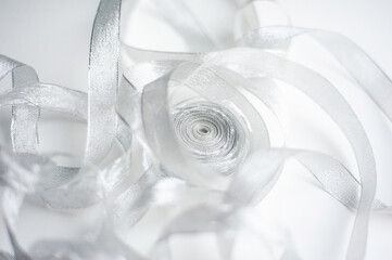 Unrolling skein of silver ribbon. Photography in a light key. Overexposure as an effect. Wedding concept. Decorative concept. Close-up