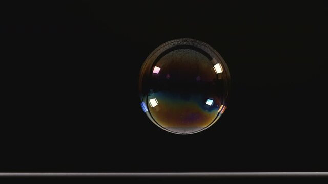 The bursting of a big soap bubble. slow motion