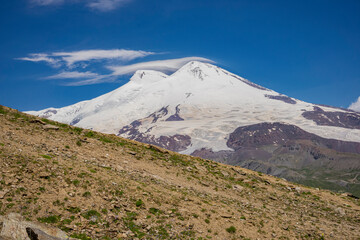 Mount Elbrus. Landscape view in the south-east of mount from Cheget mount. Kabardino-Balkaria region, Russia. Its west top and east top top are covered with clouds. They appeared in the afternoon
