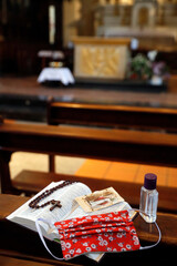 Coronavirus epidemic (COVID-19). Bible, alternative mask and hydroalcoholic gel in a church. Social distancing.