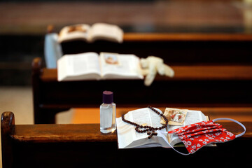 Coronavirus epidemic (COVID-19). Bible, alternative mask and hydroalcoholic gel in a church. Social distancing.