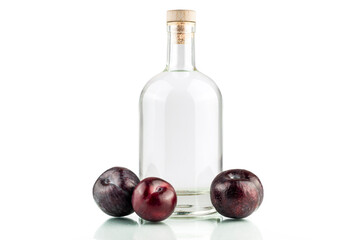 Transparent glass bottle with alcohol liquid isolated and plums on white background.