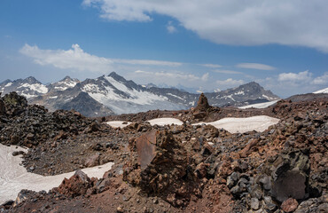 Pieces of solidified lava of the Elbrus volcano against the background of mountains and glaciers of the Main Caucasian ridge