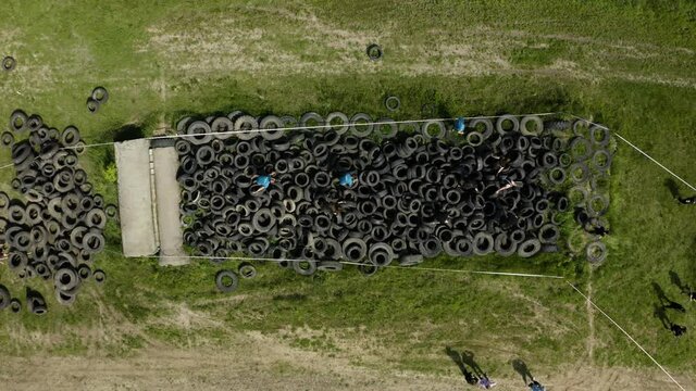 Man Running Through Tires As Part Of An Assault Course. Man Running Through Tires. Aerial View.  Men Competing In An Modern Obstacle Course.