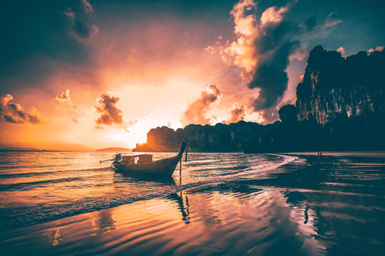 Amazing sunset with longtail boats silhouette at Railay beach, Thailand.