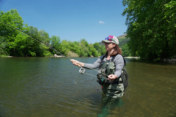 young woman fly fishing in summer in large river