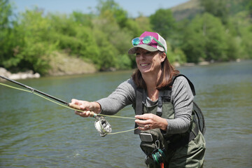 young woman fly fishing in summer in large river