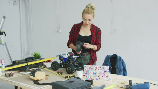 Woman playing with radio-controlled car in workshop