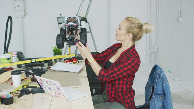 Woman examining radio-controlled car in workshop