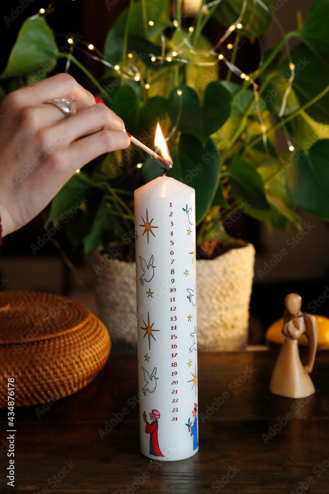 Wall mural woman lighting a christmas advent candle. france.