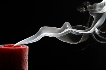 Curling smoke from one extinguished advent candle on black background.  France.