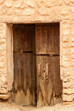 An old, wooden, dilapidated door in an abandoned house. Oasis of Mides, Tunisia, North Africa