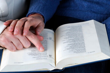 Naklejka premium Man and woman reading together the bible at home. Christian couple living in the love of God and Jesus. France.