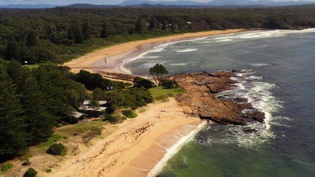 Beach flyby over rocky outcrop