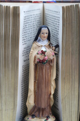 Bible and Saint Therese de Lisieux figurine. Also known as Saint ThÃ©rÃ¨se of the Child Jesus and the Holy Face.  France.
