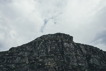 Dark atmospheric minimal landscape with silhouette of rocky mountain under cloudy sky. Minimalist...