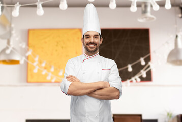 cooking, culinary and people concept - happy smiling male chef in toque and jacket with crossed arms over restaurant background - obrazy, fototapety, plakaty