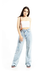 Obraz premium Beautiful trendy young woman with small handbag in jeans and tank top posing. Full body length isolated on white background