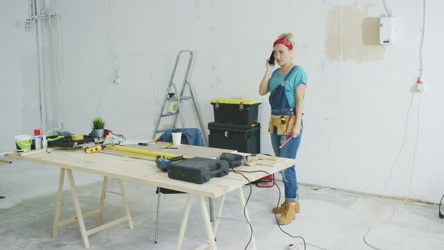Cheerful female carpenter talking on smartphone