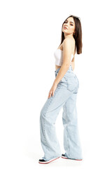 Side view of confident attitude young woman in jeans and white top posing at camera. Full body length isolated on white background