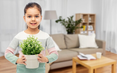 environment, nature and people concept - happy smiling girl holding flower in pot over home background