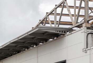Metallic awning of modern warehouse. Metal framework of roof of industrial premises in enterprise outside view. Structure of steel roof frame