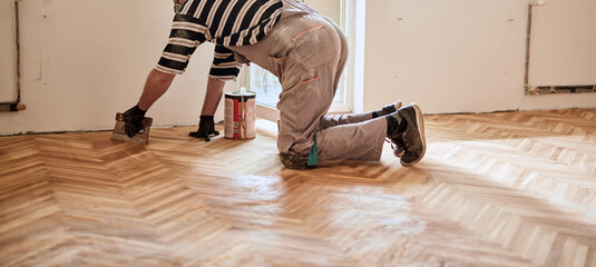 Repairman restoring old parquet hardwood floor.