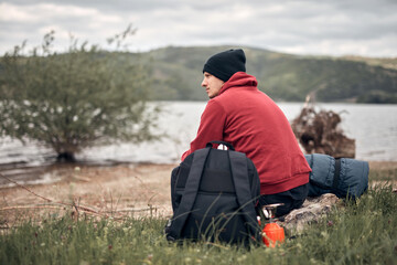 Naklejka na ściany i meble Hiker camping in nature on a river shore.