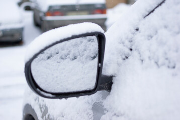 Snow-covered car. Side mirror under snow