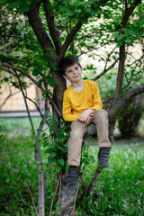 boy on the tree. portrait of a child resting on a branch. yellow t-shirt and cap.