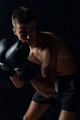 Fototapeta na wymiar boxer in gloves on a black background bent down 