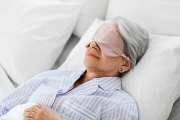 old age and people concept - senior woman with eye mask sleeping in bed at home bedroom