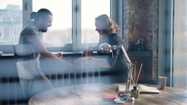 Funny real-time footage shot through the blinds. Two co-workers a woman and a man are having fun at the office while doing the cleaning.