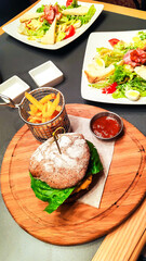 beef burger with ketchup and fries on wooden desk on table at restaurant. hamburger bun with salad leaf and cheese