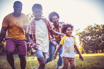 Fototapeta premium African American family having fun outdoors. Focus is on woman face. Happy family enjoying in the nature.