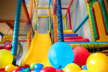 Multicoloured plastic balls in a dry pool with a slide in the indoor playroom of a children's park