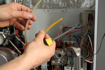 A man checks a gas boiler for home heating. Maintenance and repair of gas heating