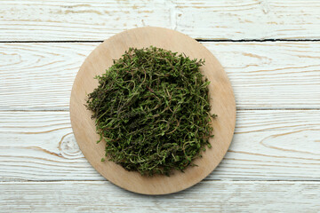 Board with thyme on white wooden background