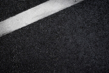 Top view of dark wet asphalt road with white line. High resolution full frame textured background of black asphalt, viewed from above. Copy space.