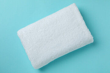 White folded towel on blue background, top view