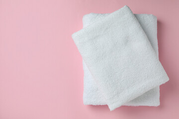 Clean folded towels on pink background, space for text