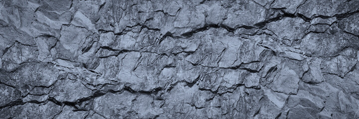 Gray rock texture with cracks. Stone wall background with copy space for text and design. Wide banner. Rocky surface. Close-up.