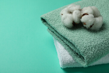 Clean folded towels and cotton on mint background