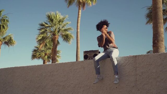Happy Afro man having fun listening to music with vintage boombox stereo in tropical place during summer vacations