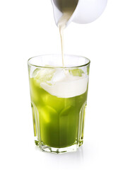 Milk pouring into glass with matcha iced tea isolated on white background.
