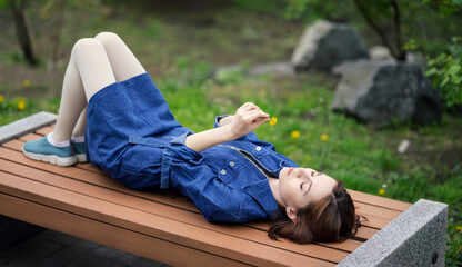 Portrait of beautiful calm woman. She is lying on a park bench.