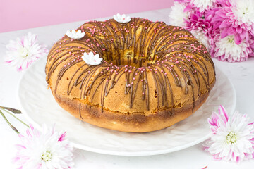 A big cupcake against a chrysanthemum. A cupcake with oranges and candied fruit. Chocolate ganache and white sugar daisies